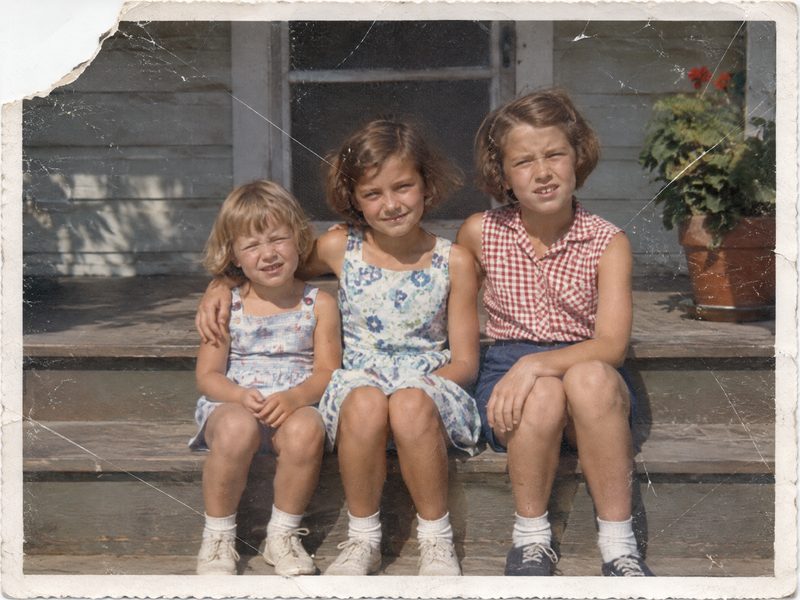 Before: a 1950s snapshot of three sisters on porch steps with a torn-off corner and many scratches
