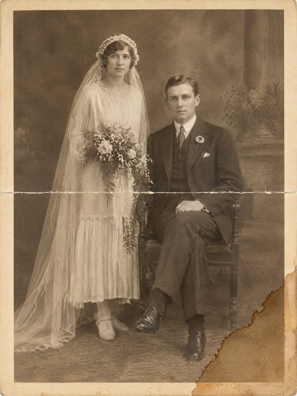 Before: a 1920s sepia wedding portrait folded across the middle, with a brown water stain in the lower-right corner